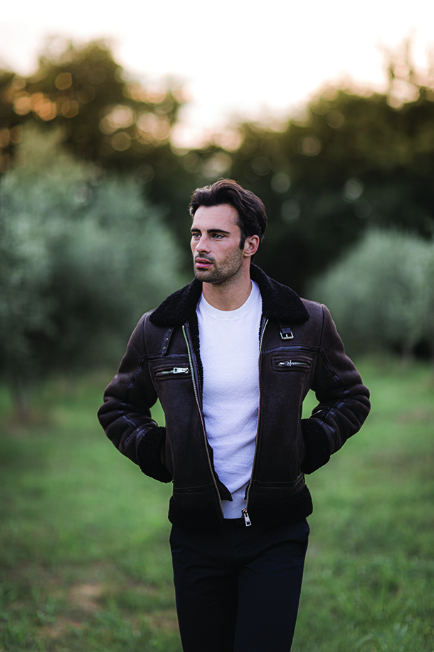 Man in leather jacket walking through an olive grove in Tuscany
