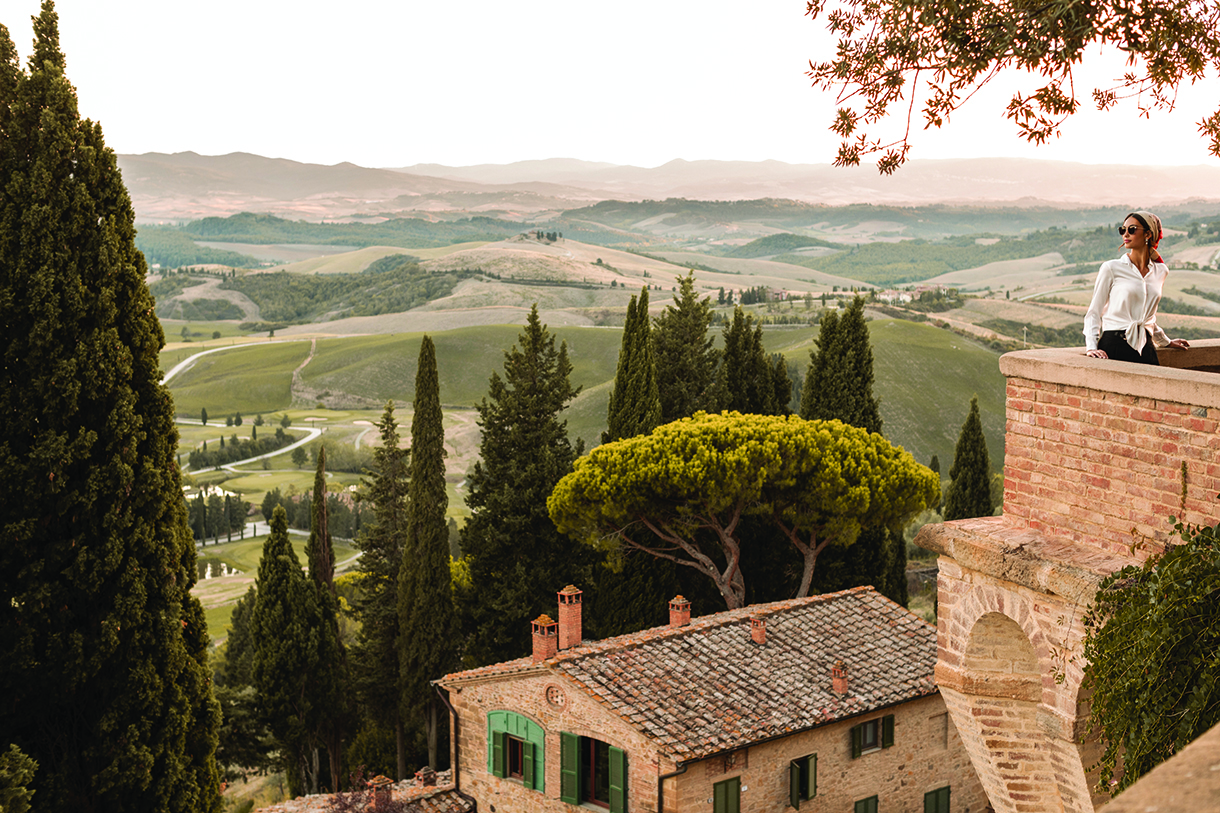 Woman on rooftop looking out on Tuscany hills