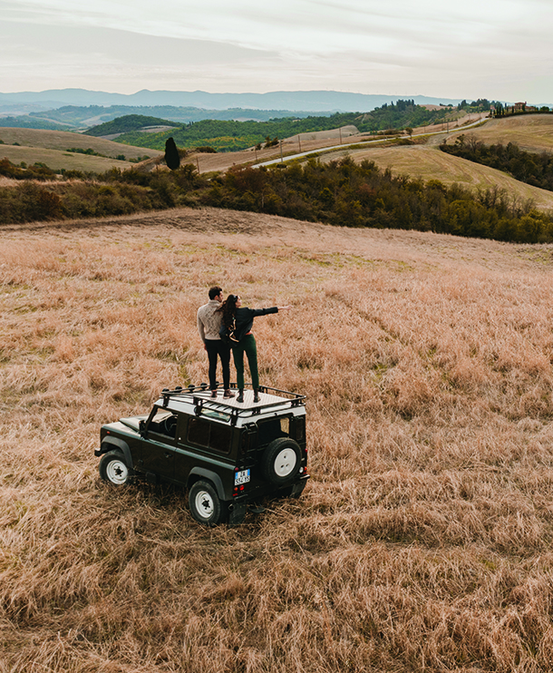 Couple standing on top of Land Rover Defender