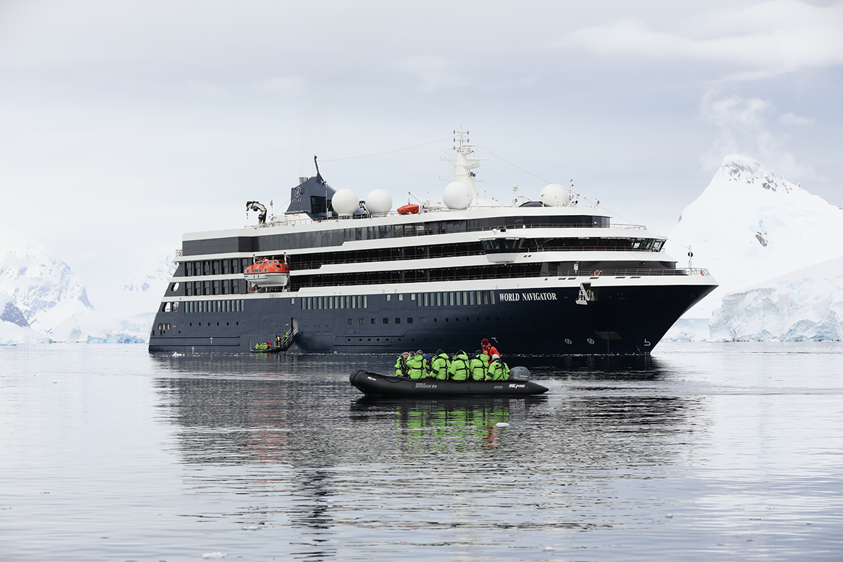 World Navigator ship and Zodiac near an iceberg in icy Antarctic waters