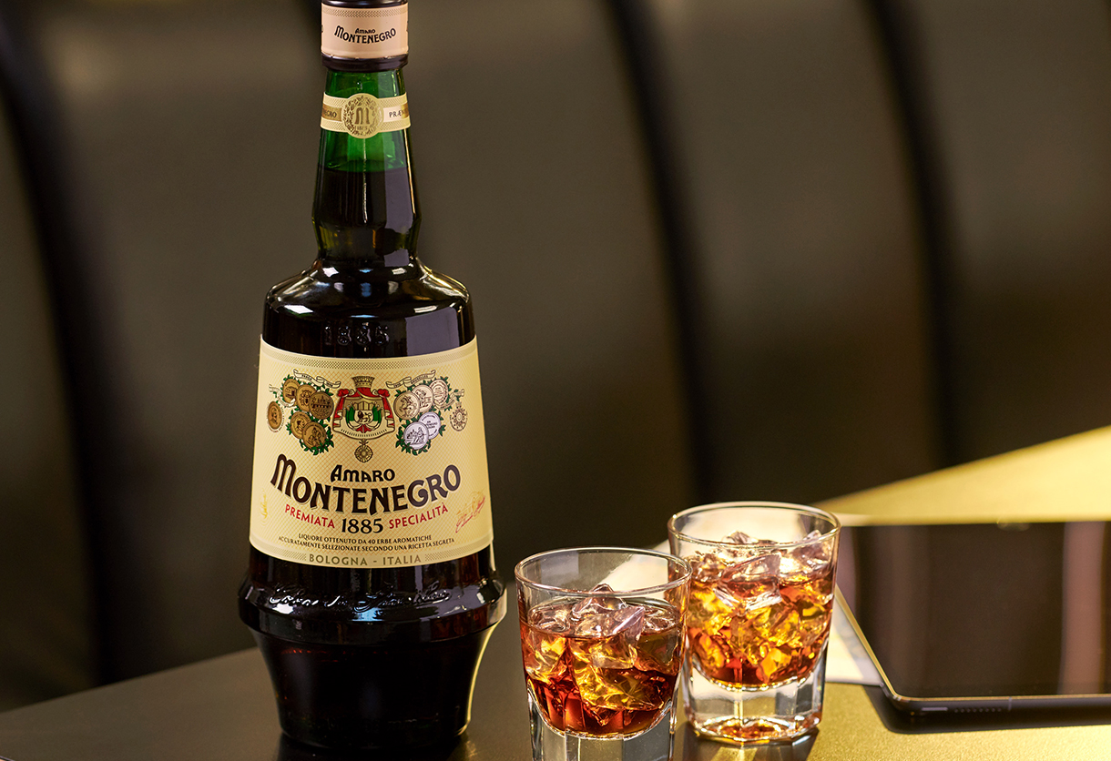 An Amaro Montenegro bottle with 2 filled tumblers on a table