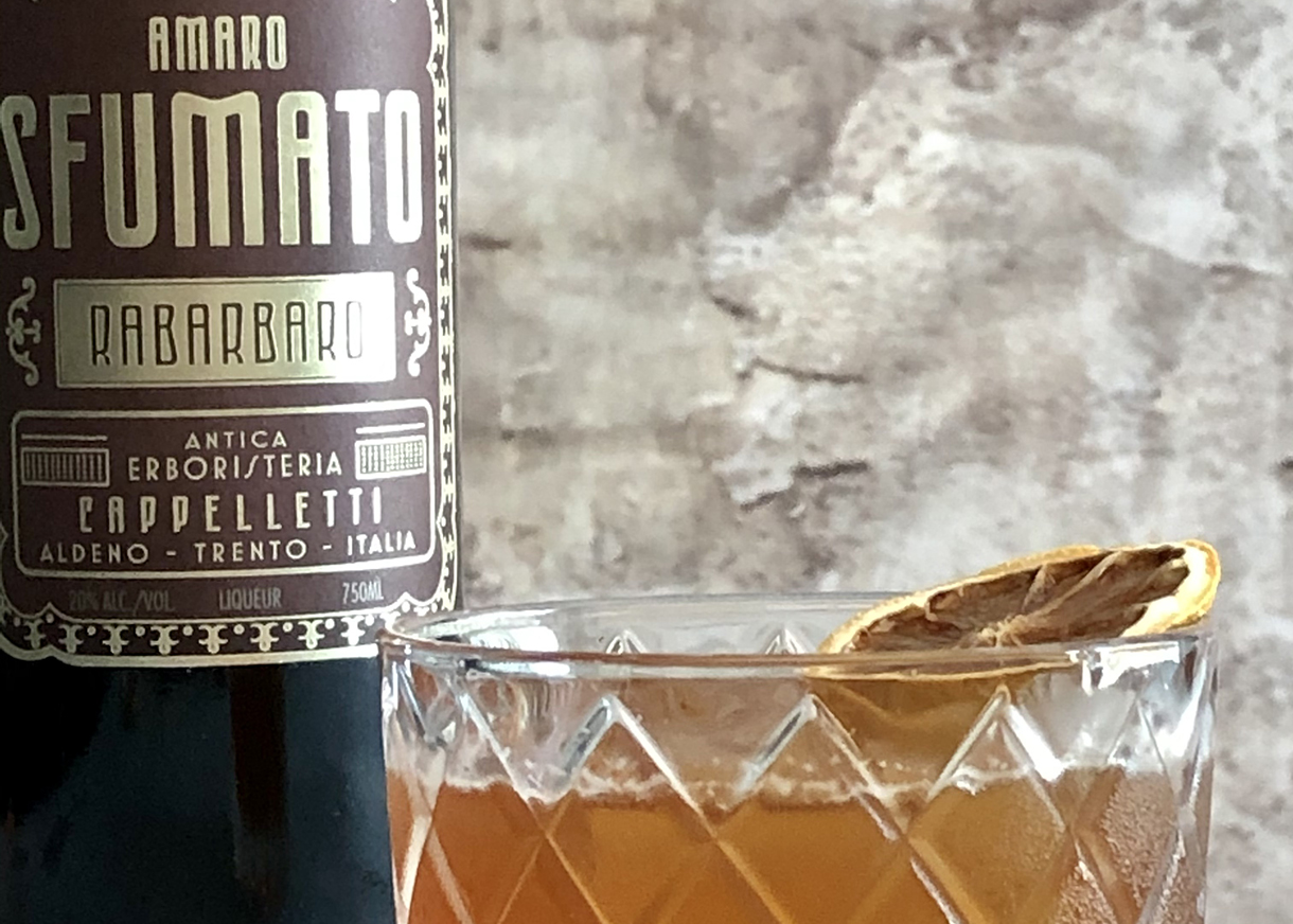 Amaro Sfumato Rabarbaro bottle next to filled tumbler garnished with dried citrus