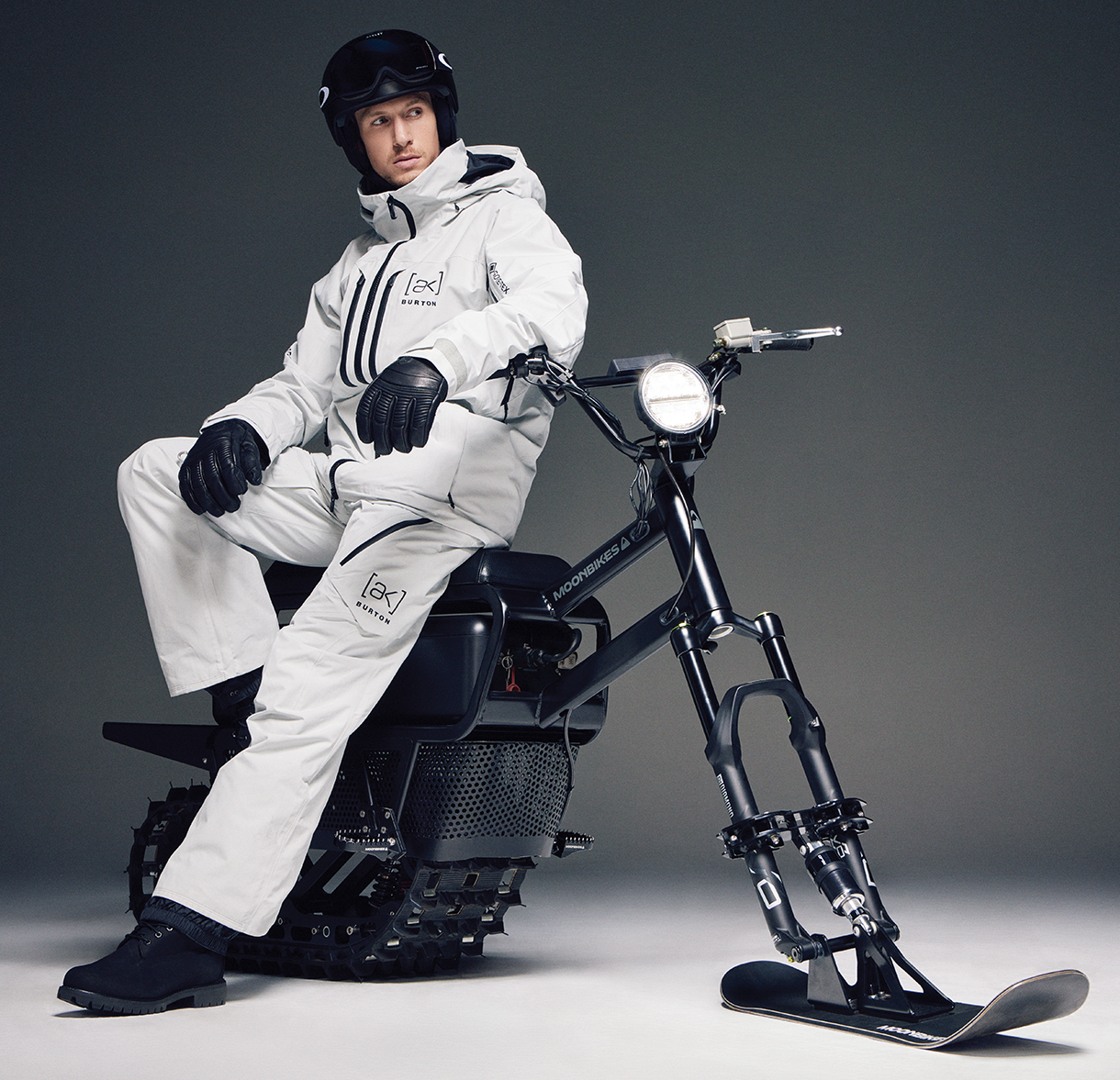 Man with snow apparel and helmet sitting on black Moonbike