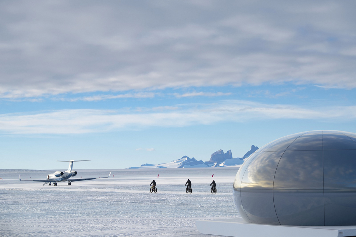 Guest fatbike across Antarctica’s icy white terrain. There is a private jet and mountains in the distance.