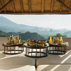 A picnic set up on a dining terrace with a beautiful view that overlooks a lush green mountain range.