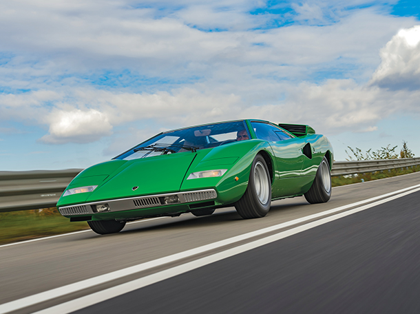 A vibrant green Lamborghini Countach 1974 speeds down a scenic road