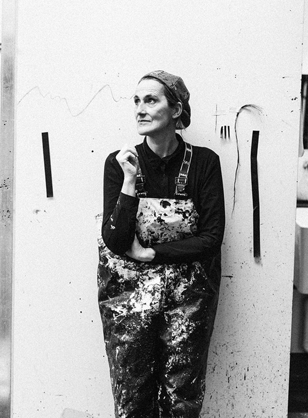 Black and white photo of a female painter wearing overalls covered in paint