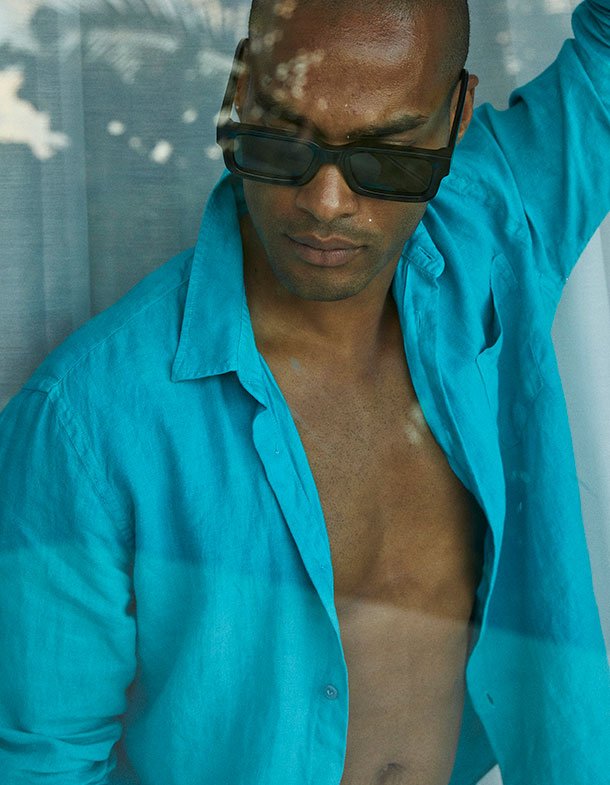 Man wearing turquoise button down linen shirt and dark sunglasses
