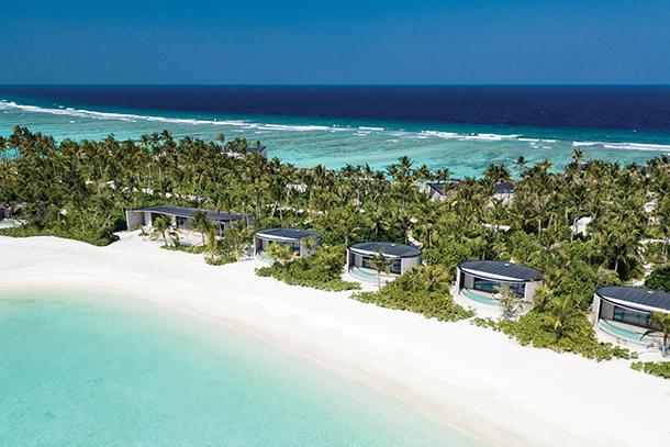 Modern island resort with circular wooden villas surrounded by lush palm trees and cast along the white sandy beaches