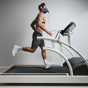 Man wearing breathing mask while running and doing an exercise test on a treadmill