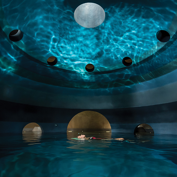 Woman floating in water inside dome-shaped indoor wellness pool