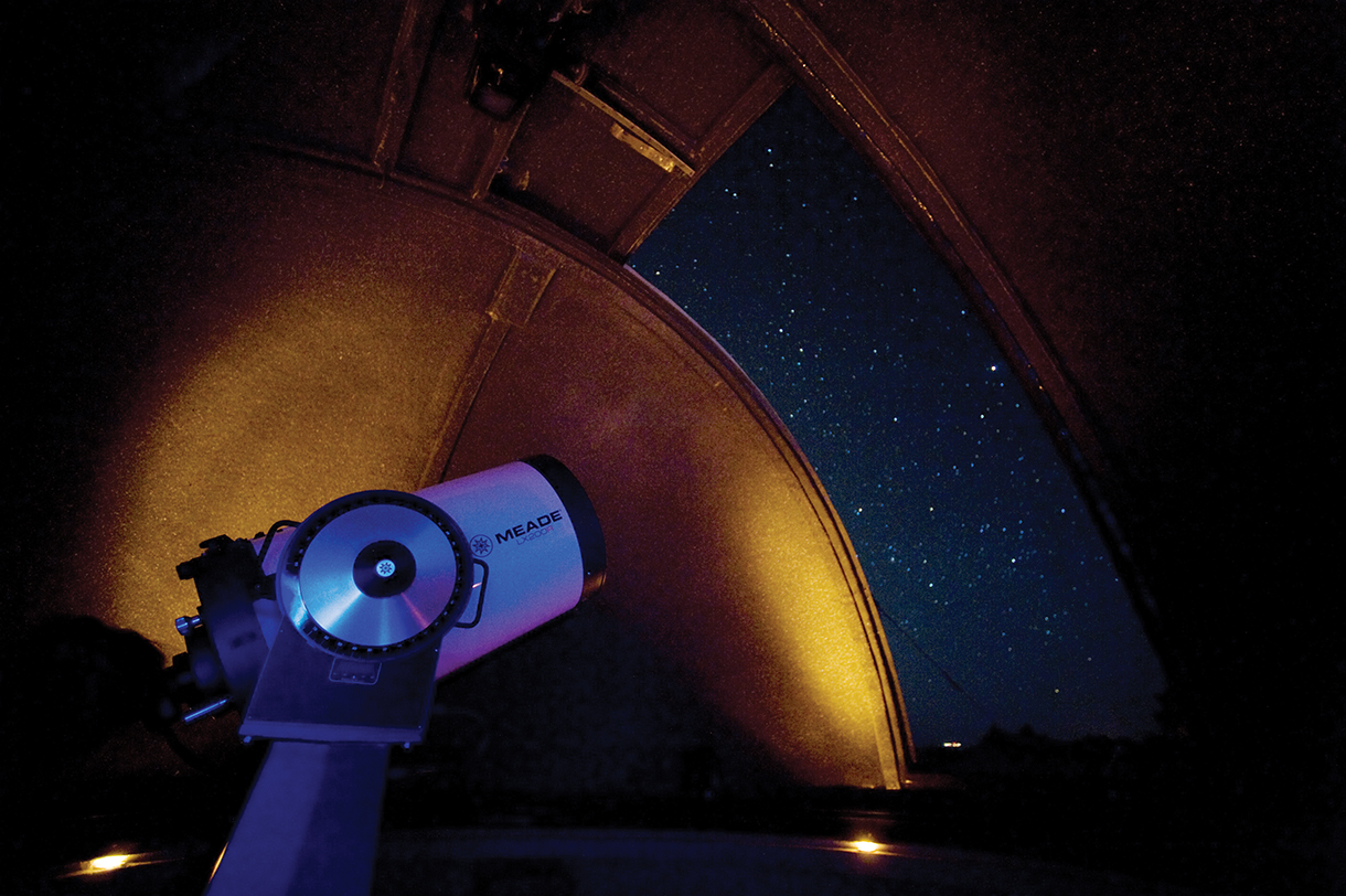 Closeup of radio telescope inside an observatory at night 