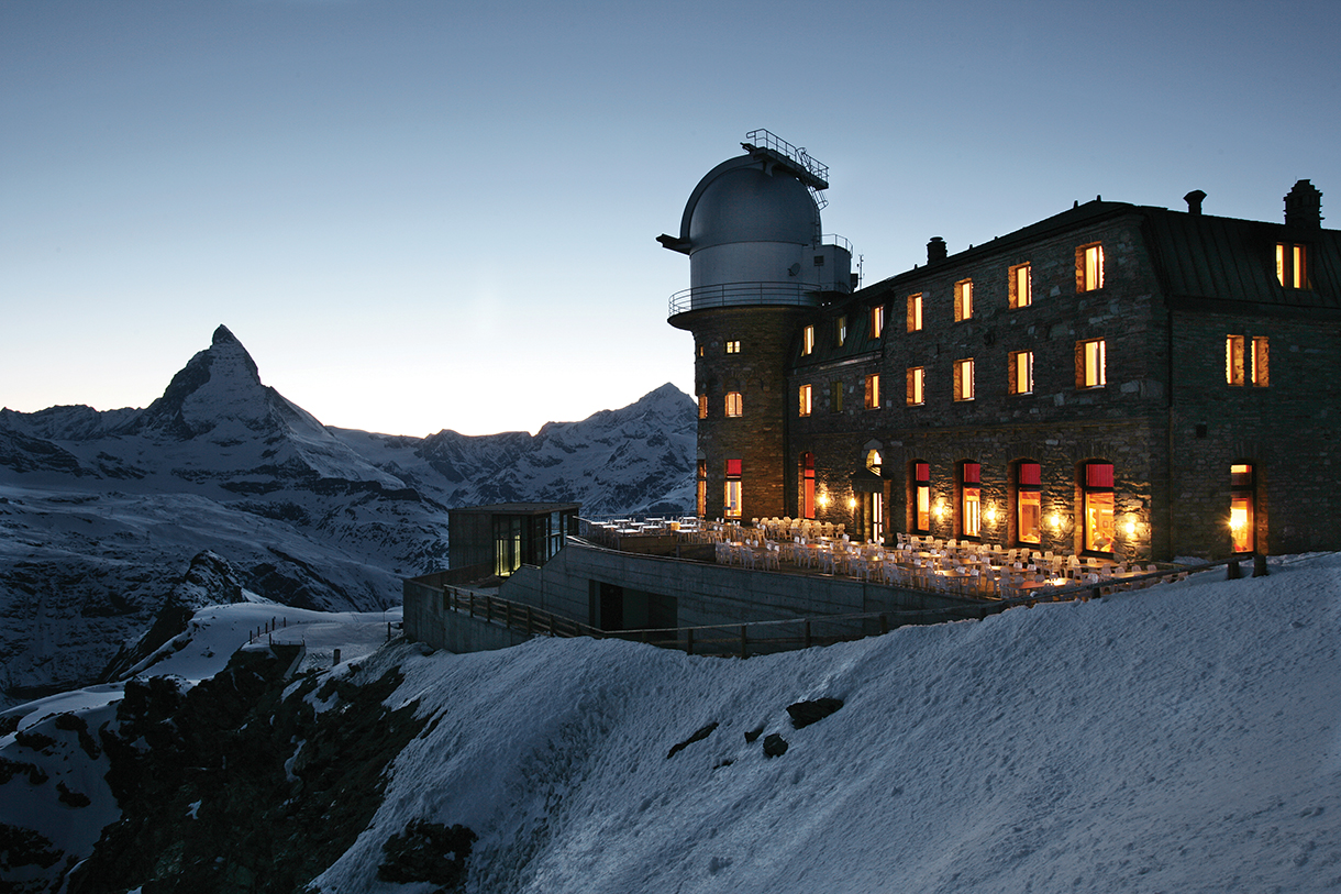 Hotel with observatory at dusk located on top of a mountain in Swiss Alps