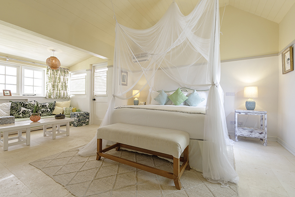 Interior of Cottage bedroom with a white canopy bed, multiple windows and a sitting area