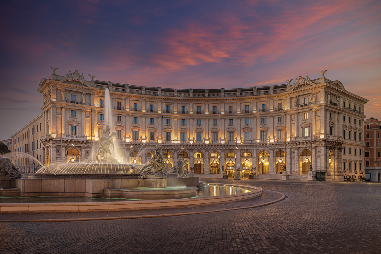 Hotel with classical Roman architecture and water fountain with bronze sculptures in front