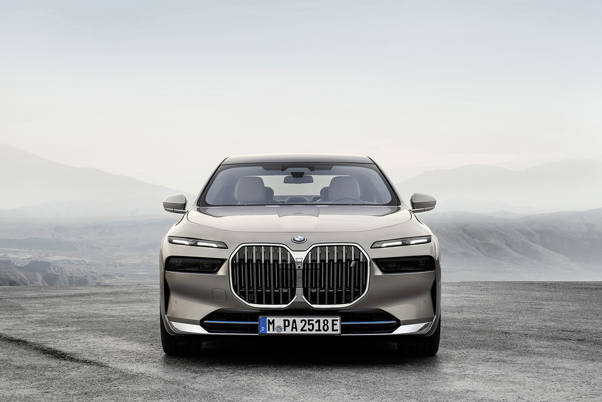 Closeup of the front view of silver BMW i7 xDrive60  with mountains in the background