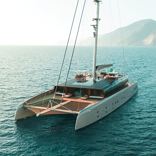 Aerial view of a large, modern catamaran yacht named ArtExplorer. The yacht is designed for luxury and sustainability, with a focus on environmental responsibility. It has a sleek and modern design with a spacious deck and plenty of outdoor living space.