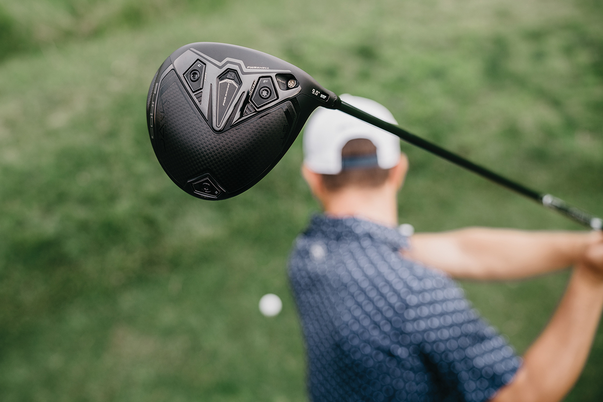 A male golfer hitting a golf ball with a black Cobra Darkspeed LS driver. There is a close-up view of the performance golf club head.