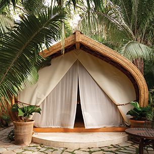An outdoor spa pod or room built from wood and canvas inspired by the shape of the ceiba tree seed. It is used for private spa treatments at a luxury resort nestled in the tropical forest. 