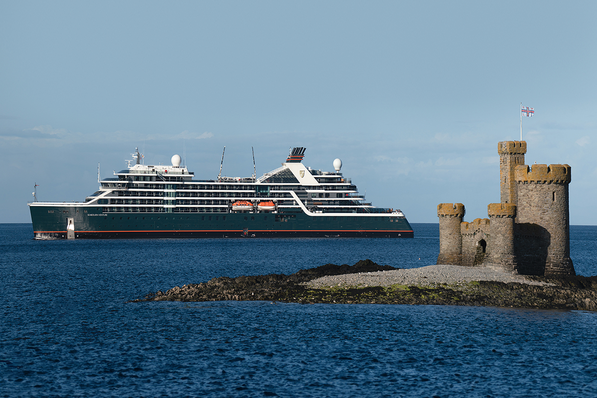 A large cruise ship, the Seabourn Venture, sailing in the ocean near the Tower of Refuge on St. Mary’s Isle in Douglas Bay, Isle of Man.