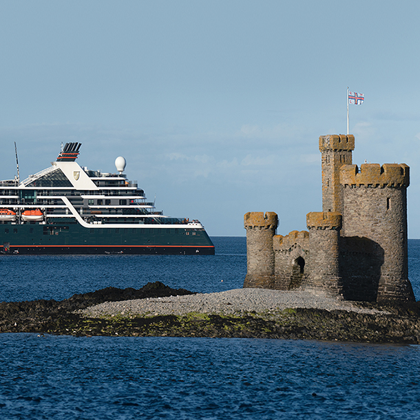 A large cruise ship, the Seabourn Venture, sailing in the ocean near the Tower of Refuge on St. Mary’s Isle in Douglas Bay, Isle of Man.