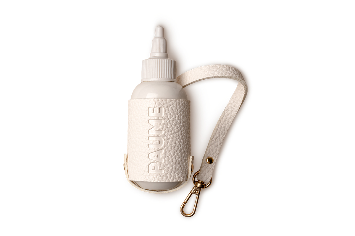 A 3-ounce size Paume Sanitize On the Go Duo antibacterial gel in a chic off-white vegan leather Voyager Pouch with backpack clip perfect for travelers.