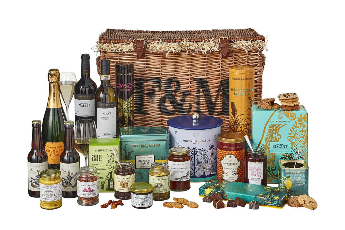 A wicker basket from Fortnum & Mason filled with gourmet treats including special blends of tea, jars of tangy marmalade, bottles of claret, or tins of biscuits