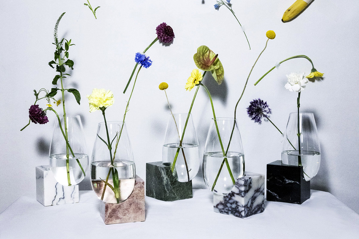 Swedish designer, Anni Cernea's Cliffhanger vases are mouth-blown crystal vases balanced on different types of marble blocks. The vases have a variety of flowers in them.