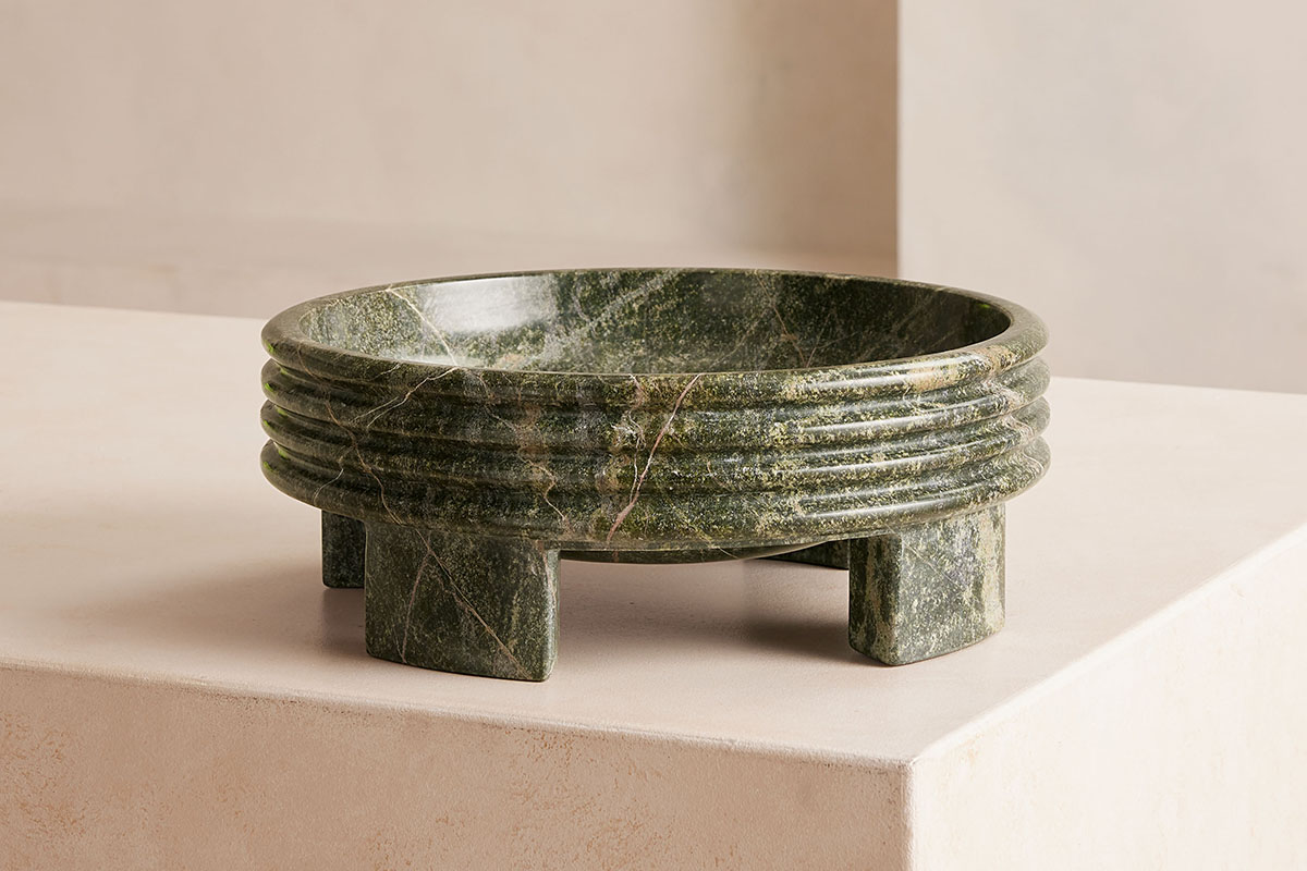 Inspired by Brutalist architecture, the Charlecote green marble bowl from Soho Home features a ridged design and an elegant sculptural form sits on a light peach background.