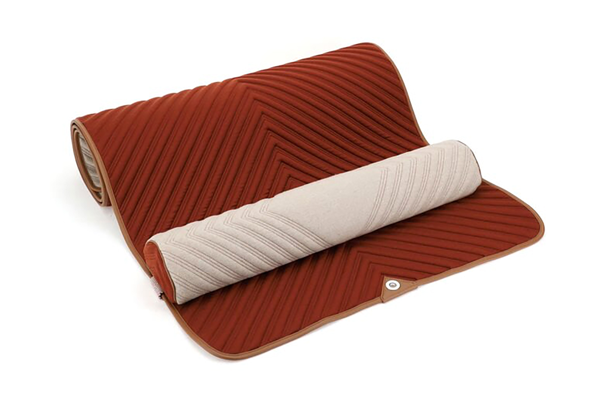 Cashmere meditation mat with dark red orange on one side and cream on the other side, featuring a cheveron pattern with leather trim and soft matching pillow.