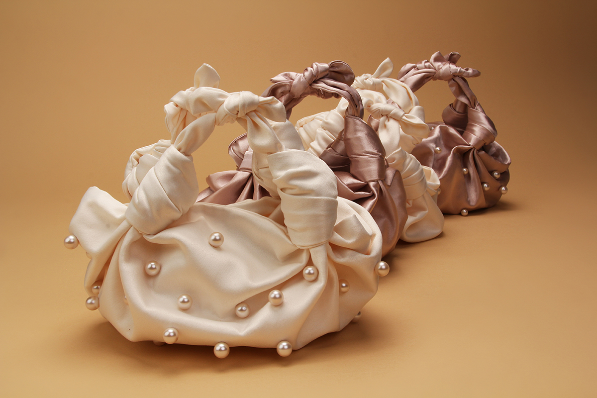 Line up of silky satin evening bags adorned with ivory pearls in different shades. Founded by  Natalie Amoils , NLA Collection is handmade in Los Angeles and features an invisible magnetic closure. 