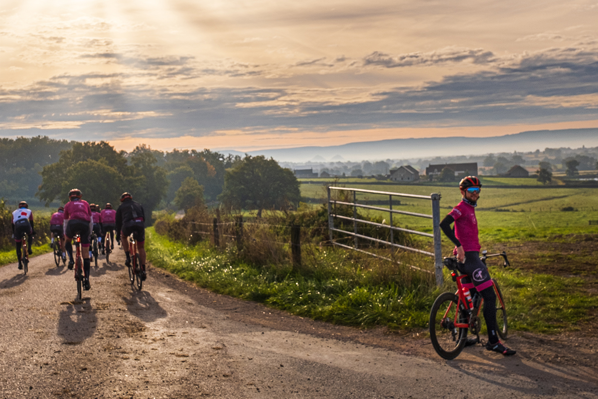 Group of cyclists in the Paris Coquillade Challenge riding down country road at sunset. They are riding from Paris to the Coquillade resort in the south of France.
