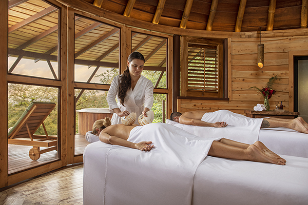 A serene spa treatment room where a couple are getting massages. The image conveys a sense of relaxation and rejuvenation, with a focus on the therapeutic benefits of massage and the tranquil atmosphere of the spa.